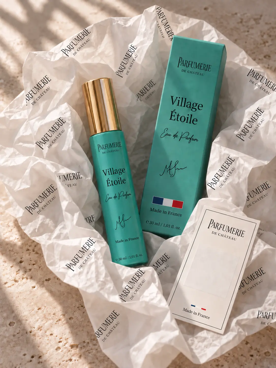 A turquoise Parfumerie de Château bottle wrapped in crisp branded tissue paper